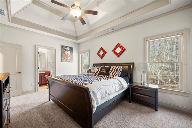 bedroom featuring a tray ceiling, light colored carpet, visible vents, ensuite bath, and baseboards