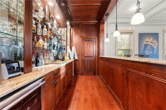 bar with pendant lighting, crown molding, a bar, wood finished floors, and beverage cooler