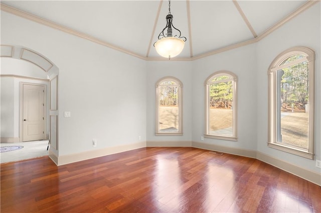 unfurnished room featuring lofted ceiling, crown molding, baseboards, and wood finished floors