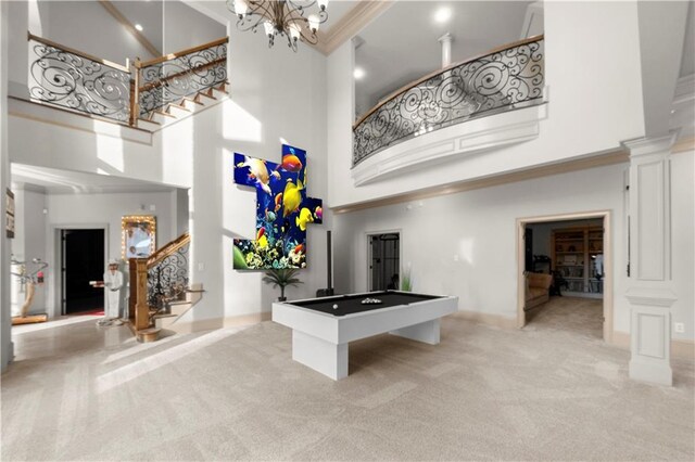 rec room featuring ornamental molding, light carpet, a towering ceiling, and ornate columns