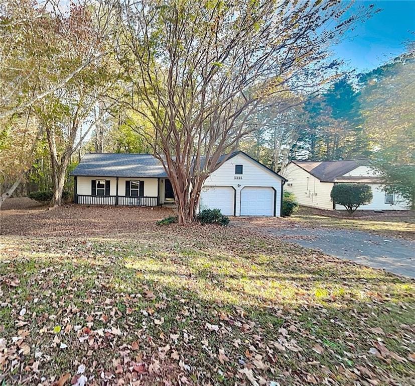 view of front of house featuring a porch, a garage, and a front lawn