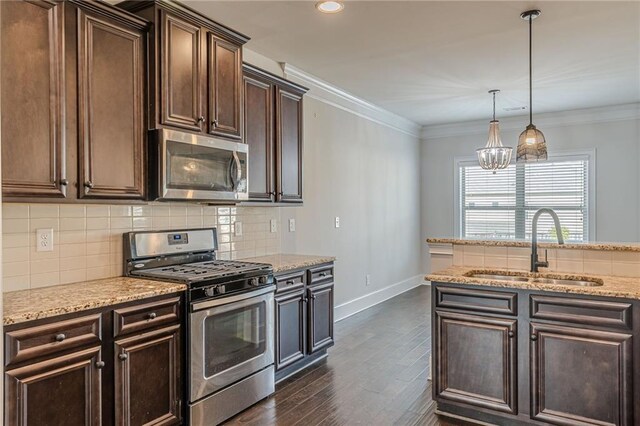 kitchen featuring pendant lighting, sink, crown molding, and stainless steel appliances