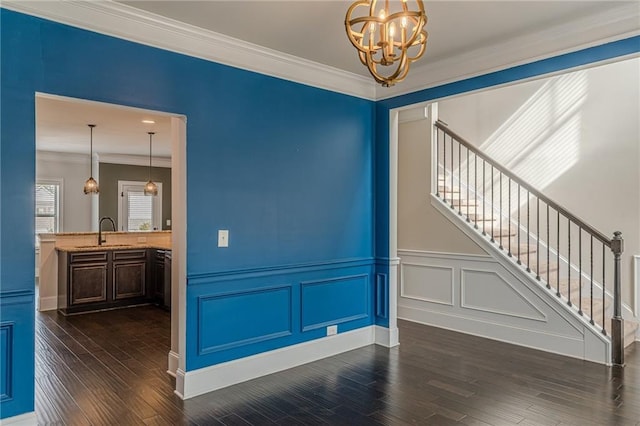 spare room with sink, crown molding, dark wood-type flooring, and a chandelier