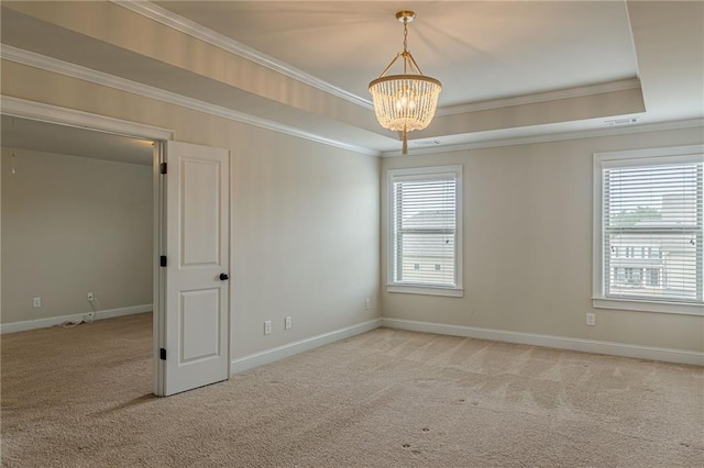 carpeted empty room featuring a raised ceiling, crown molding, and a notable chandelier