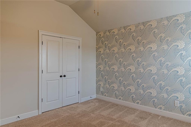 unfurnished bedroom with lofted ceiling, light colored carpet, and a closet