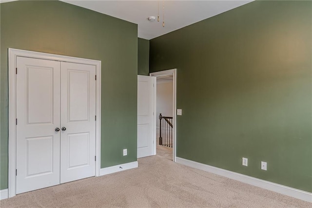 unfurnished bedroom with light carpet and a closet