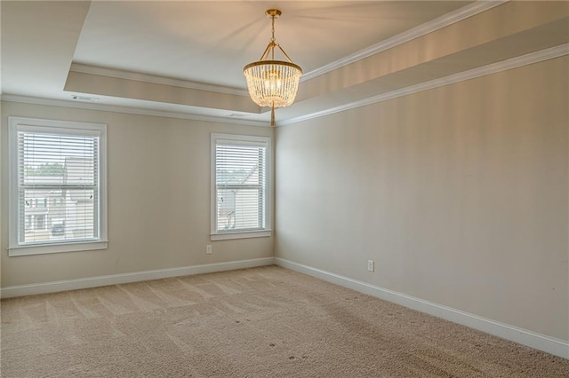 carpeted empty room featuring an inviting chandelier, ornamental molding, and a tray ceiling