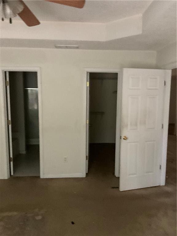 unfurnished bedroom featuring a walk in closet, ceiling fan, visible vents, baseboards, and a closet