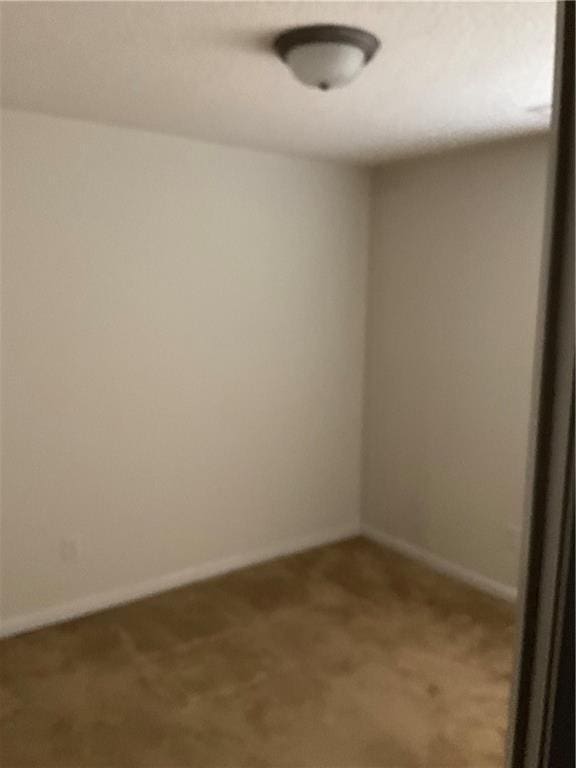 spare room with baseboards and light colored carpet