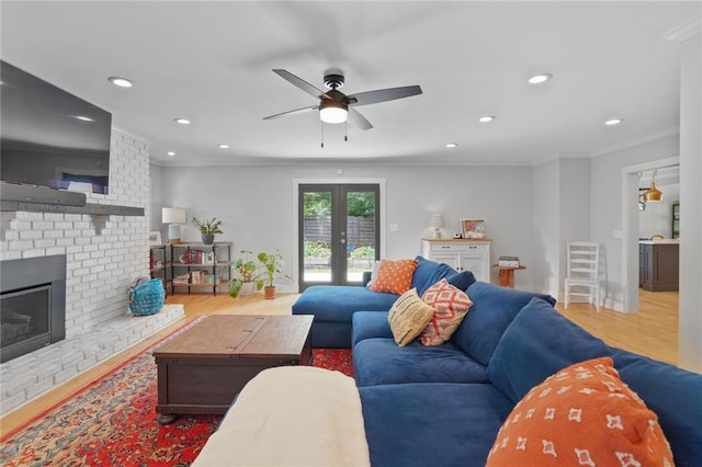 living area featuring wood finished floors, recessed lighting, ornamental molding, a brick fireplace, and ceiling fan