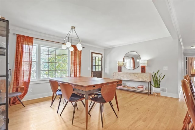 dining space with baseboards, light wood-type flooring, and crown molding