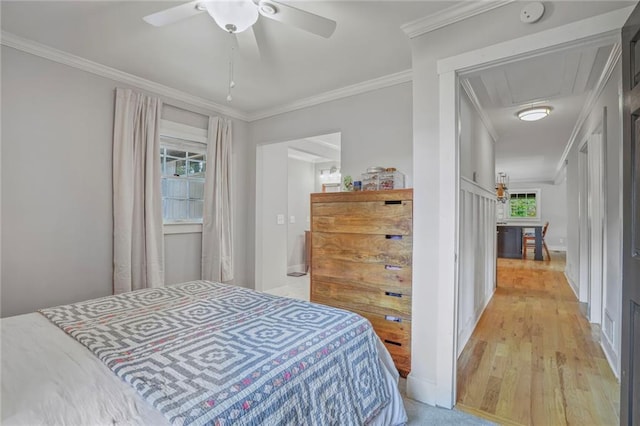 bedroom with attic access, ornamental molding, light wood-style flooring, and a ceiling fan
