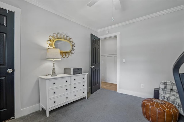sitting room with dark carpet, ornamental molding, a ceiling fan, and baseboards