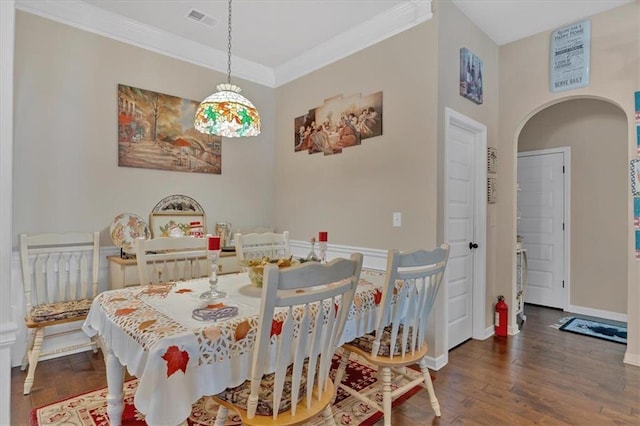 dining area with dark wood-type flooring and crown molding