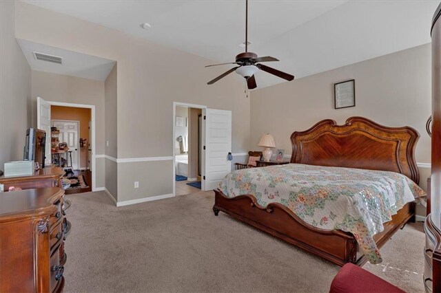 bedroom featuring connected bathroom, vaulted ceiling, light carpet, and ceiling fan