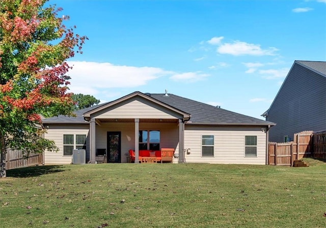 rear view of house with central AC and a yard