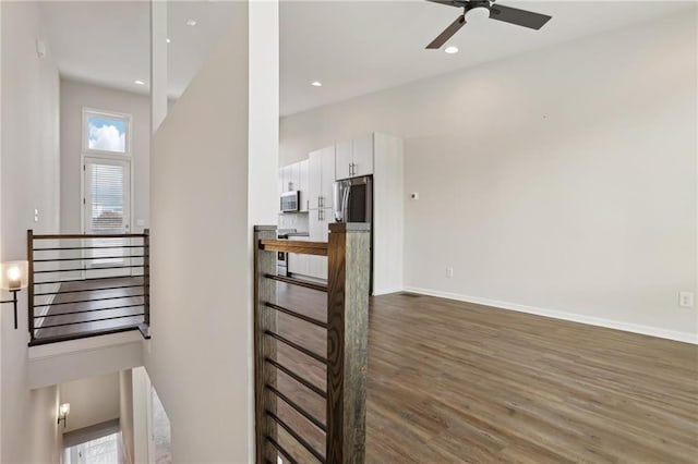 interior space featuring ceiling fan, wood-type flooring, and a towering ceiling