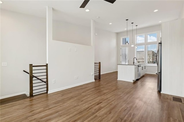 unfurnished living room with ceiling fan, dark wood-type flooring, and sink