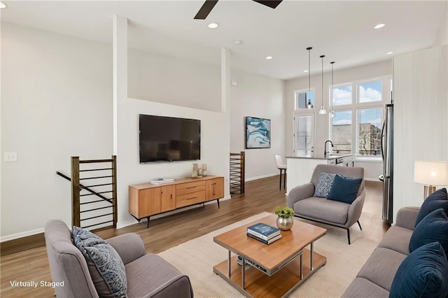 living room featuring light wood-type flooring, ceiling fan, and sink