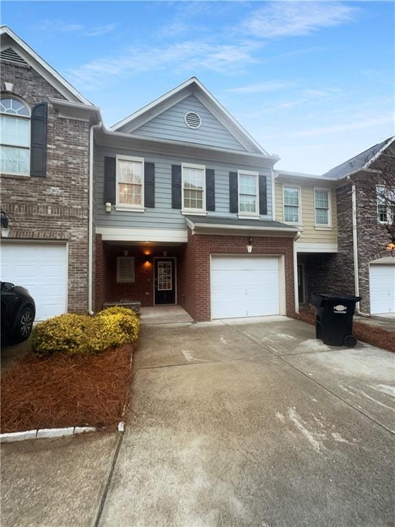 multi unit property with concrete driveway, a garage, and brick siding