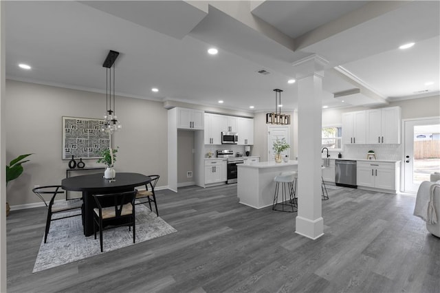 kitchen featuring white cabinetry, appliances with stainless steel finishes, backsplash, and ornamental molding