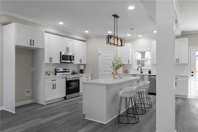 kitchen with stainless steel appliances, dark wood-style flooring, white cabinets, and ornamental molding