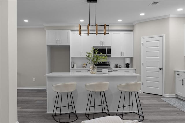 kitchen with a center island, visible vents, decorative backsplash, appliances with stainless steel finishes, and ornamental molding