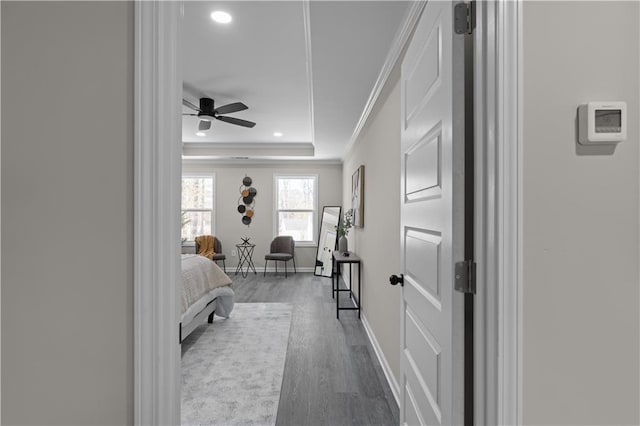 bedroom with baseboards, a raised ceiling, ornamental molding, wood finished floors, and recessed lighting