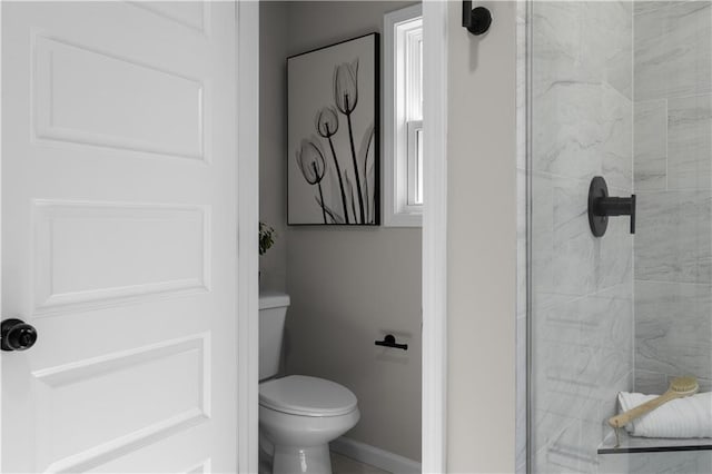 full bath featuring toilet, baseboards, and a tile shower