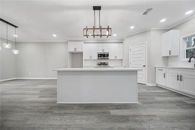 kitchen with baseboards, appliances with stainless steel finishes, white cabinets, and ornamental molding