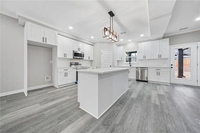 kitchen with stainless steel appliances, tasteful backsplash, light countertops, light wood-style floors, and white cabinets