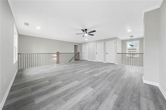 unfurnished room featuring baseboards, wood finished floors, visible vents, and crown molding