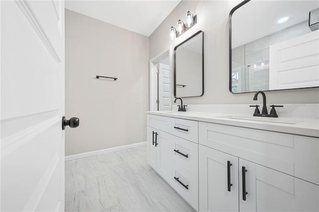 bathroom featuring double vanity, baseboards, walk in shower, and a sink