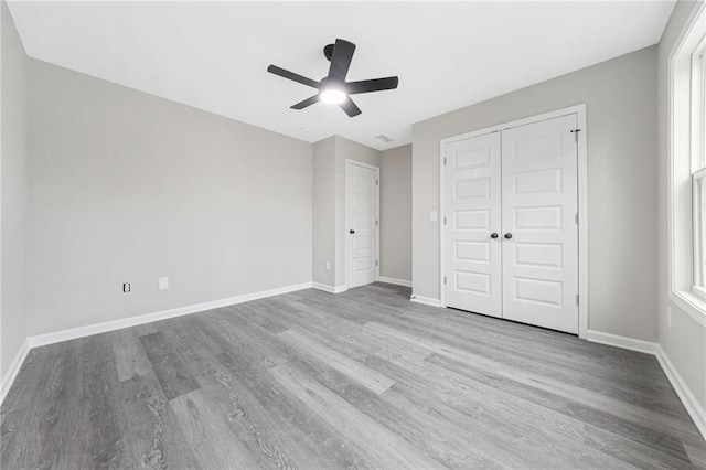 unfurnished bedroom featuring a closet, wood finished floors, a ceiling fan, and baseboards