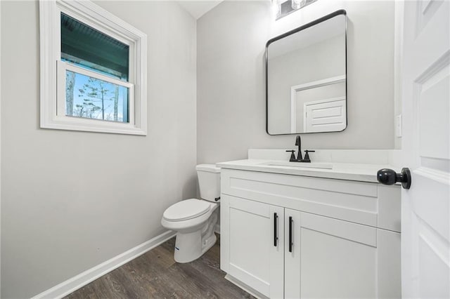 bathroom featuring toilet, baseboards, wood finished floors, and vanity