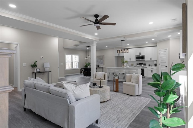 living area with recessed lighting, wood finished floors, a ceiling fan, decorative columns, and crown molding