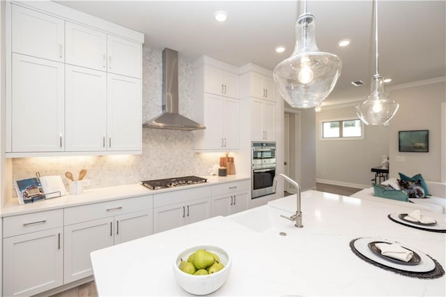 kitchen featuring wall chimney range hood, white cabinetry, appliances with stainless steel finishes, and backsplash