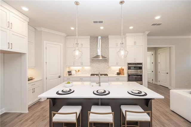 kitchen featuring ornamental molding, backsplash, visible vents, and wall chimney range hood