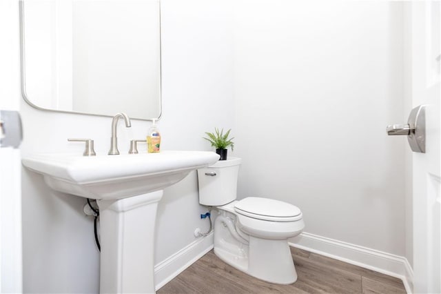 bathroom with toilet, baseboards, and wood finished floors