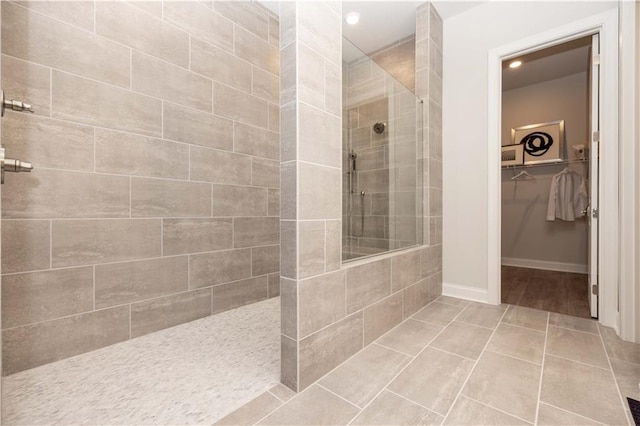 full bathroom with tile patterned flooring, a spacious closet, baseboards, and walk in shower