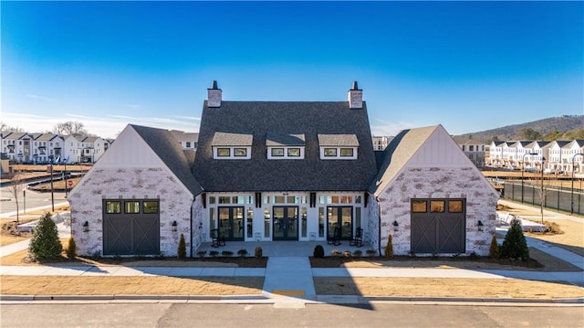 view of front of house featuring a garage, stone siding, a chimney, and a residential view