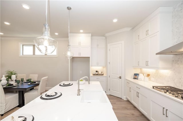 kitchen featuring tasteful backsplash, white cabinetry, stainless steel gas cooktop, and a sink