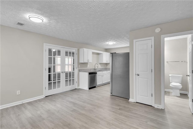 7185 Sweet Gum Ct, Lithonia, GA 30058 - kitchen featuring a textured ceiling, white cabinets, a sink, stainless steel appliances, and french doors