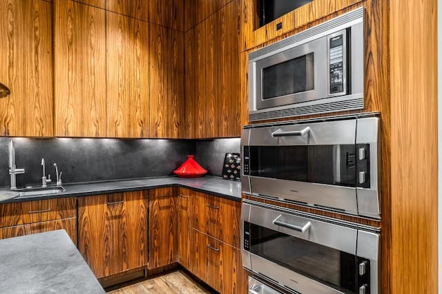 kitchen featuring light hardwood / wood-style flooring, sink, stainless steel appliances, and tasteful backsplash