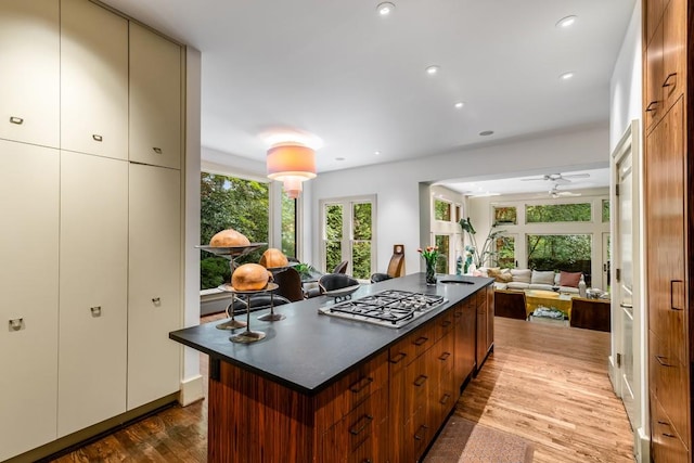 kitchen featuring ceiling fan, a kitchen island, light wood-type flooring, and stainless steel gas stovetop