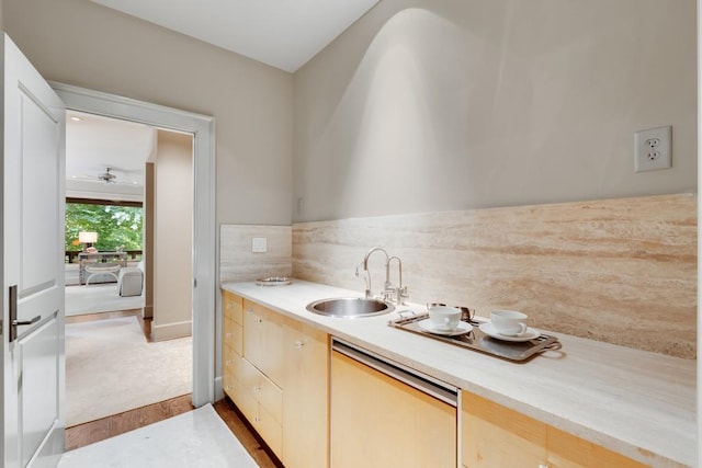 kitchen featuring stainless steel dishwasher, ceiling fan, sink, light brown cabinets, and light hardwood / wood-style floors