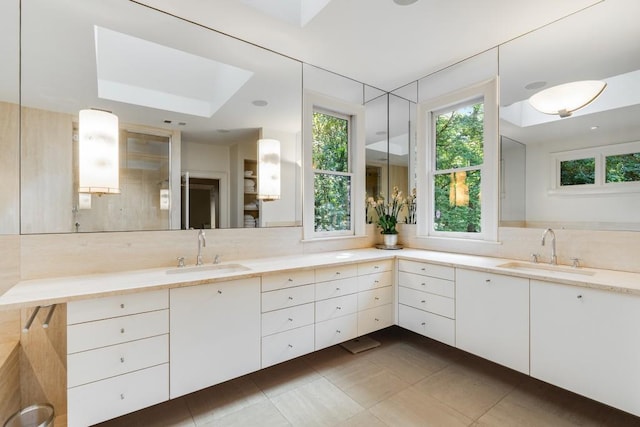 bathroom featuring tile patterned floors, a skylight, decorative backsplash, and vanity