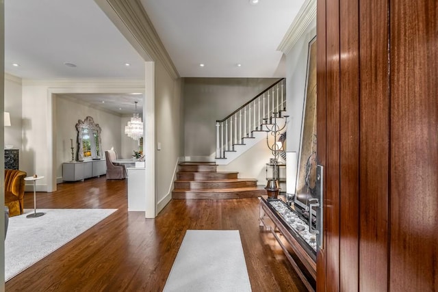 foyer entrance with dark hardwood / wood-style flooring, ornamental molding, and a chandelier