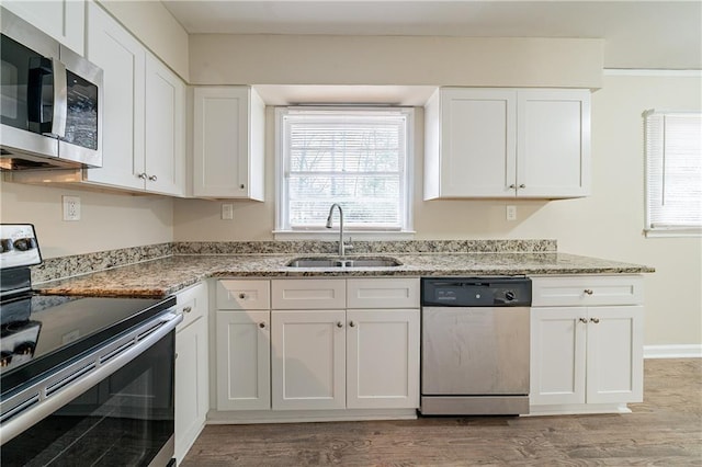 kitchen featuring appliances with stainless steel finishes, light stone countertops, sink, and white cabinets