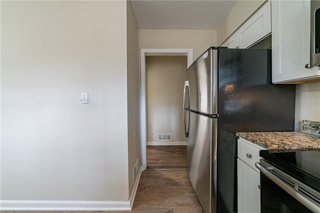 2104 Barbara Ln, Decatur, GA 30032 - kitchen featuring wood-type flooring, dark stone counters, white cabinets, and appliances with stainless steel finishes
